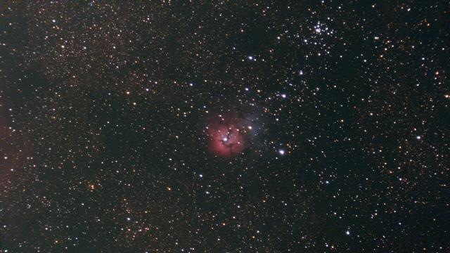 A dense field of stars with a small blob of red and blue gas at the center
