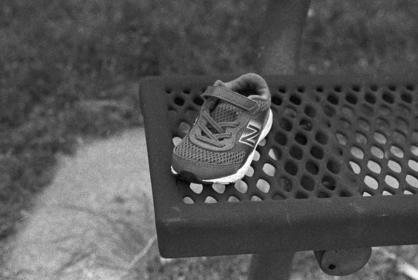 A tiny athletic shoe left behind on a park bench.