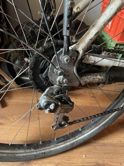 the dropout of a bicycle frame on the drive side. The chain is kept taut with an old Shimano chain tensioner
