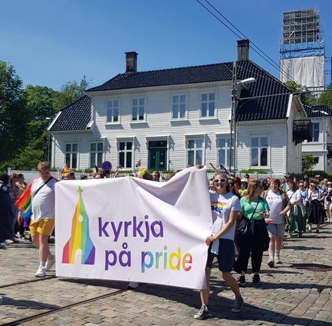 Real photograph of a fragment of the pride parade in Bergen, Norway. A banner with the text "Kyrkja på Pride" - meaning The Church participates in the parade, or at least some representatives. Real photographer: me.