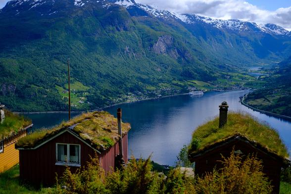 A view of Nordfjorden from Rakssetra. Cute little cabins overlook a fjord. The water is dark blue green. The valley is covered in green forest with snow capped mountains in the distance.

Shot with a Fujifilm X-T30II + Fujinon XF 35mm f2.0 lens