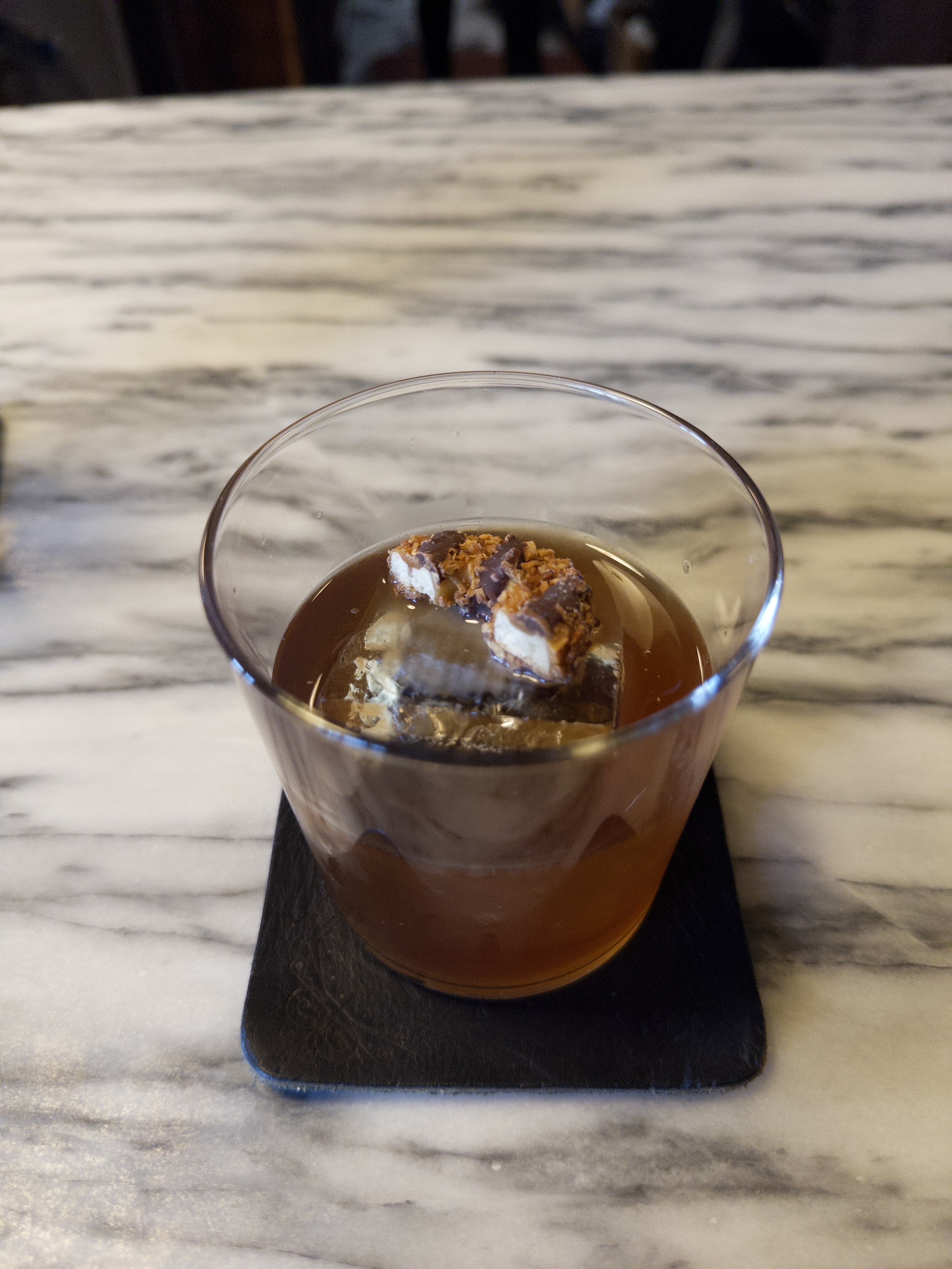 A clarified milk punch based on the Boulevardier cocktail (bourbon, Campari and sweet vermouth) garnished with half a Samoa cookie