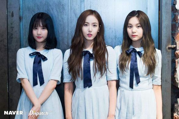 The image features three individuals standing side by side in front of a blue wooden door. They are wearing matching light blue dresses with short sleeves and dark blue bows at the neck. The dresses have a simple, classic design with pleats at the waist. The individuals have different hairstyles: the person on the left has short, straight black hair, the person in the middle has long, wavy brown hair, and the person on the right has long, straight brown hair. The background is a weathered blue door with visible wood grain and a brick wall on the right side. The lighting is soft and even, highlighting the subjects and the texture of the door. The image includes a watermark in the bottom left corner that reads "NAVER Dispatch HD."

Provided by @altbot, generated privately and locally using Ovis2-8B