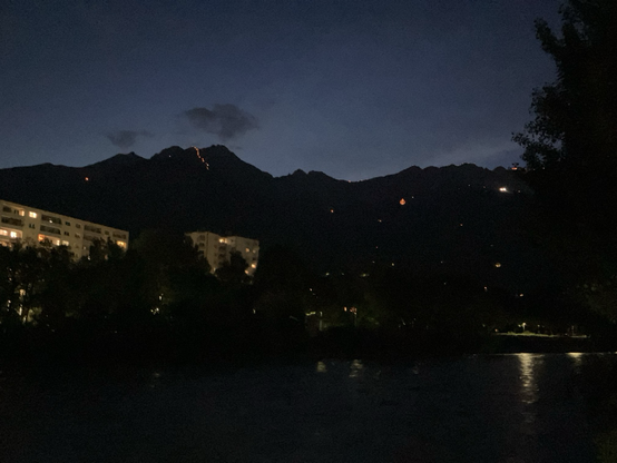 innsbrucks nordkette im dunkeln, mehrere feuer. ein großes feuer in form einer vulva über der höttinger alm.