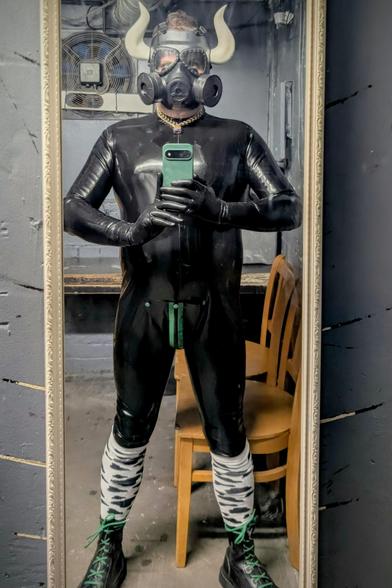 A mirror selfie.
Me in full black, shiny latex hugging every inch of my body. Capped off with a gasmask with bullhorns clipped on.