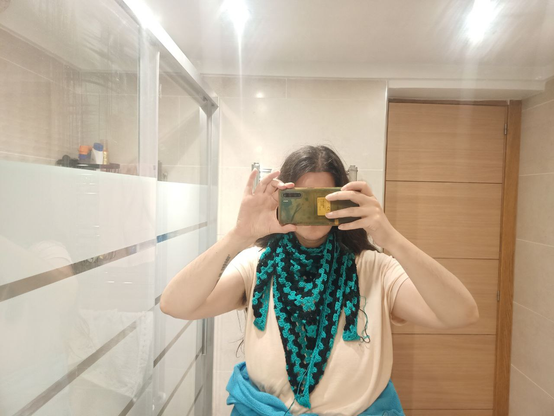 Selfie en el espejo del baño, anonimizada por poner la cámara a la altura de la cara y vistiendo el Emochal, a franjas verdeazuladas y negras, como pañuelo. El pico central cae hasta el ombligo, mientras que los picos laterales dan la vuelta al cuello y se quedan a mitad.