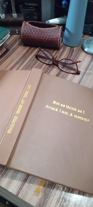 The same book, placed pages down on a desk. The binding reads: "Not think...Am drunk: Whatever."