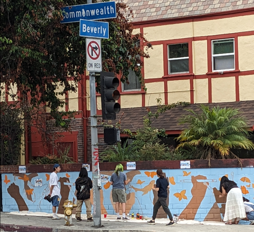 People painting a mural on a cinder block wall