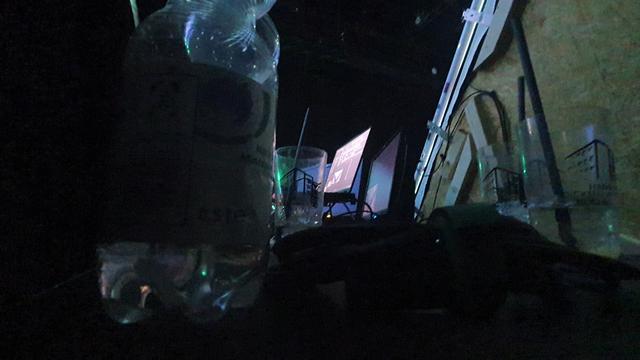 Laptop in between 3 empty Tschunks from the previous artists and an half empty water bottle. You can see the MDF backgrounds of the projection screens on the right.