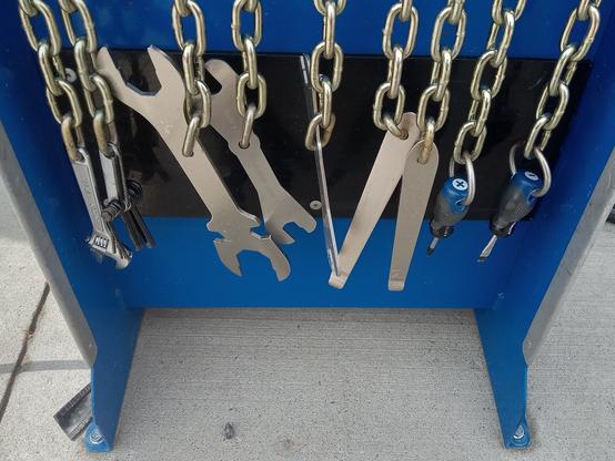 A selection of wrenches and screwdrivers hanging on (short, heavy) chains.