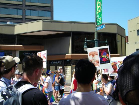 People marching in a parade carrying signs with banned book covers.