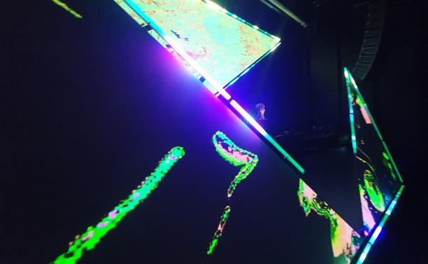 Green Lava visuals pixelated 
Furthr the DJ stands in the middle, only the head visible