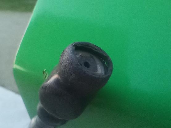 Closeup of the end of the inflation hose where the nozzle for the tire valve should be. There's a lump near the end of the hose with a magnet so the end of the hose stays attached to the green metal bike repair station.