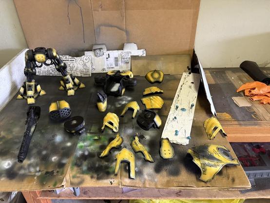 All the reaver bits are splayed out on a piece of cardboard used to backstop airbrushing. The armor panels are now yellow.