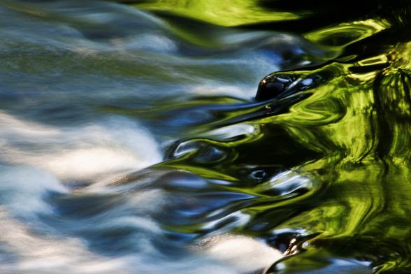 Nahaufnahme am Kanal mit längerer Belichtungszeit: Die linke Seite des Bildes ist grau-blau, das Wasser verwischt, in der rechten Seite spiegelt sich das Grün vom Ufer, hier liegt auch die Schärfe des Bildes. Es wirkt wie gemalt, ruhig und friedlich.

Close-up on the canal with a longer exposure time: the left side of the picture is grey-blue, the water is blurred, the green of the bank is reflected in the right side, this is also where the sharpness of the picture lies. It looks like a painting, calm and peaceful.
