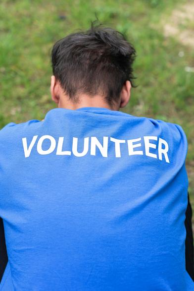 volunteer help others. blue t shirt. Dark short hair.