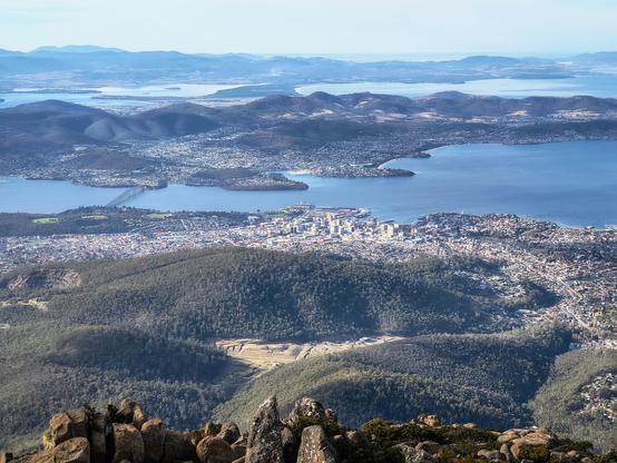 Scattered clouds over a view from the top of mountain over hills and a river and suburbs