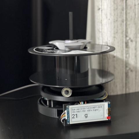 assembled, powered on horizontal loadcell-weighing universal auto rewind spool roller with an epaper display with the date, time, ip address, wireless signal and weight in grams reading 21g on an empty spool