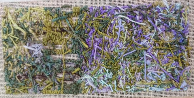 The reverse side (butt) of a stitched artwork. Lots of tangled wool threads in colours of green, blue and purple