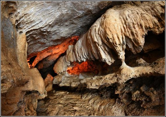 Galerie où une coulée de concrétions surplombe un ancien plancher stalagmitique.
