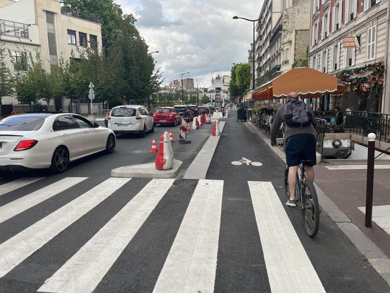 Un cycliste de dos passant un passage piéton en plateau traversant (à niveau du trottoir)