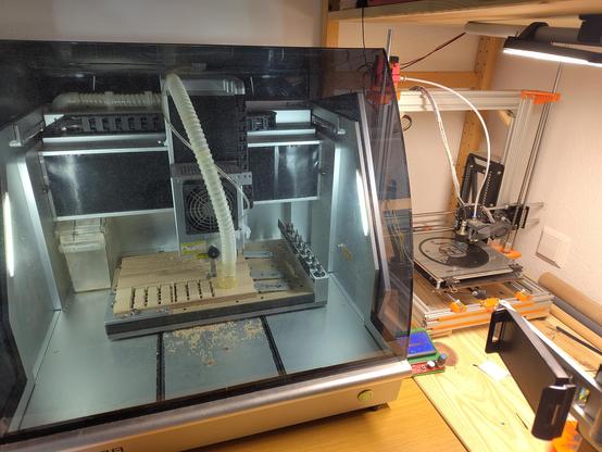 CNC Fräse und 3D Drucker stehen nebeneinander und fertigen Teile