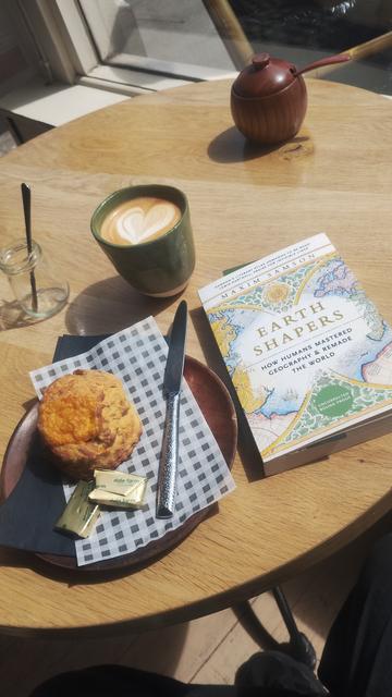 Cafe table with cheese scone, mug of coffee and book