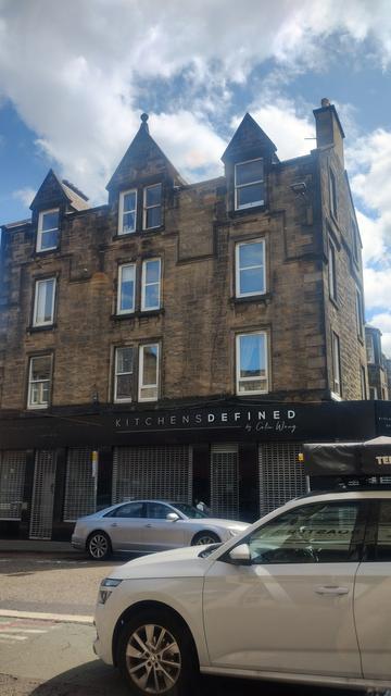 View out cafe window to Victorian stone tenements opposite, blue skies & white clouds above