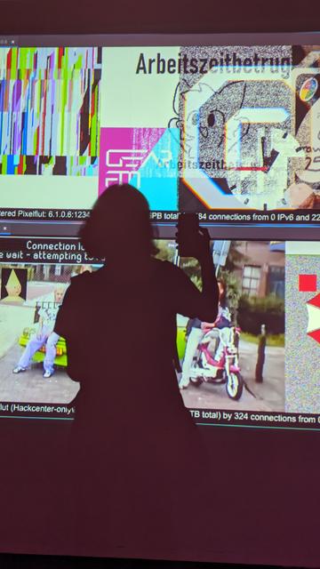 picture of my shadow on the projection of pixelflut (competitive pixel-sending wall), with a bunch of weird memes and glitches around it