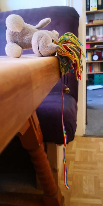 Das kleine Plüscheinhorn Carola liegt seitlich auf einem Tisch. Aufgrund ihrer Körperspannnung, liegt sie dabei nur auf linker Gesichtshälfte und Bein auf, während der Torso  in der Luft hängt und so einen Tunnel schafft.