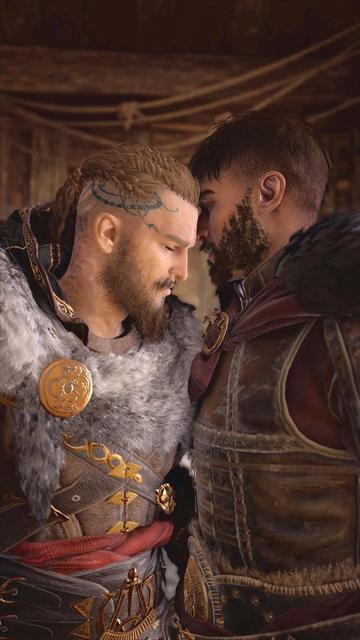 Two bearded men wearing armor, standing tenderly together.