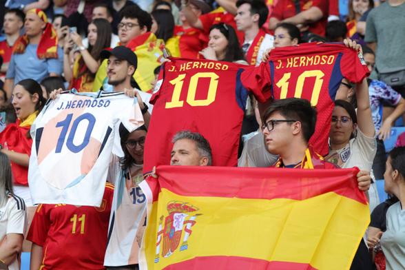 Drei Spanische Fans halten Trikots mit der Rückennummer Zehn von Jennifer Hermoso hoch. Im Vordergrund hält ein anderer eine Spanien-Flagge.