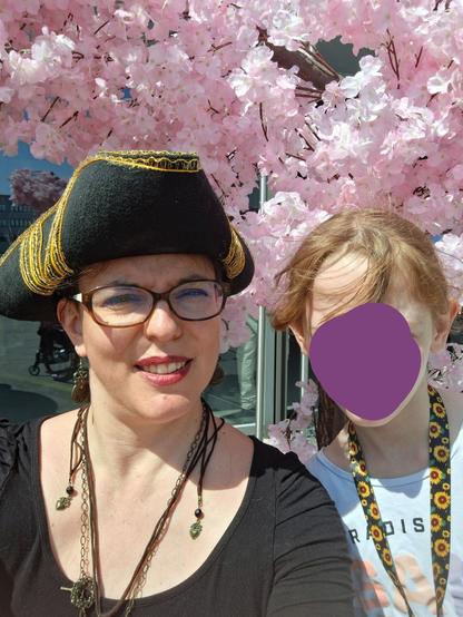 Femme de 40 ans avec un chapeau de pirate et sa fille de 8 ans avec ses cheveux roux posant devant des faux cerisiers
