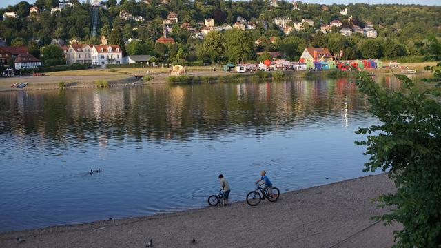 Kinder mit Fahrrad am Elbufer, Fest auf der gegenüberliegenden Seite