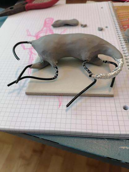 Das Skelett aus Draht und Alu hat etwas Fleisch aus grauer Modelliermasse bekommen. Beine, Schwanz und Hals bestehen aber noch aus Drahtgeflecht und stehen kahl aus dem Körper heraus.