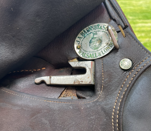 Closeup of a saddle, stirrup bar and name plate showing. J.A. Barnsby & Sons