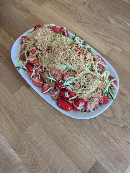 A platter of tomato and shredded courgettes with a peanut crumb.