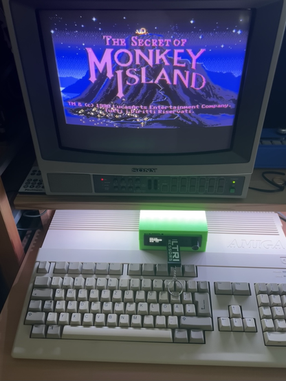 An Amiga 500 running The Secret of Monkey Island from an external Gotek in a bright green enclosure.