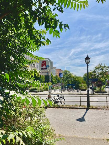 Sommerliche Straßenkreuzung mit Thermometer, das +33°C anzeigt.