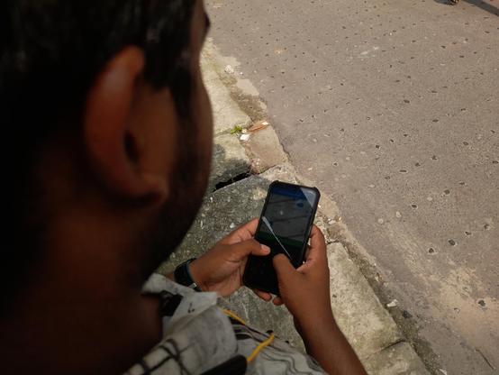 A bird's eye view of a participant mapping on his smartphone using Every Door, adding contact details of a shop.