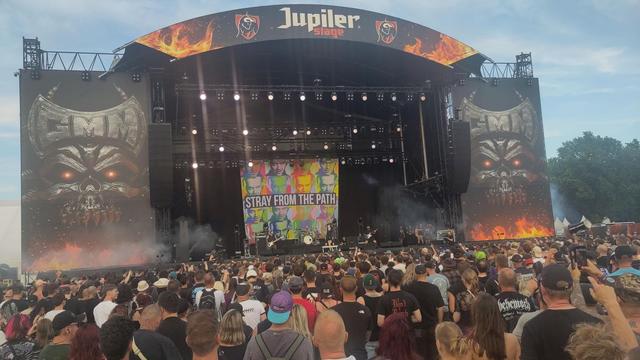 Stray From The Path op het Jupiler-podium op Graspop 2025. Achter hen een groot doek met daarop meerdere malen Jack Nicholson in verschillende kleuren en eroverheen hun naam. Er branden witte podiumlichten en aan weerszijden van het podium staat het Graspop-logo. Op de voorgrond publiek.