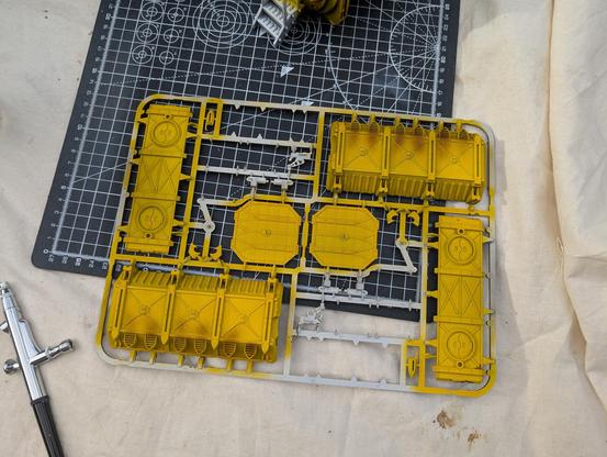 A sprue of a container painted in Iron Fists yellow with some weathering from vents in Cygor Brown. My airbrush sits in the bottom left of the picture.