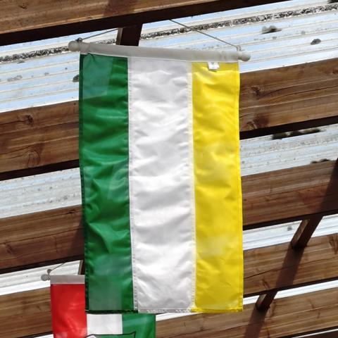 foto einer grün-weiß-gelb-gestreiften flagge, die unter einem terrassendach hängt