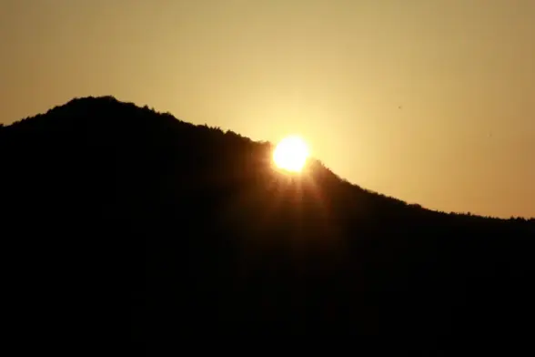 Sun shining "through a mountain" during sunset at summer solstice.
