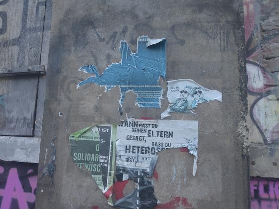 Das Bild zeigt das gleiche Plakat wie das andere Bild. Es ist größtenteils abgerissen.