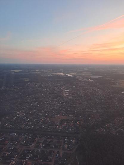 Gleicher Flug, ähnlicher Himmel, aber jetzt direkt über der Ortschaft. Man kann gut die Straßen und Häuserreihen sehen. Auf den Straßen ist nichts unterwegs. Die Straßenlaternen scheinen aber schon aus zu sein.