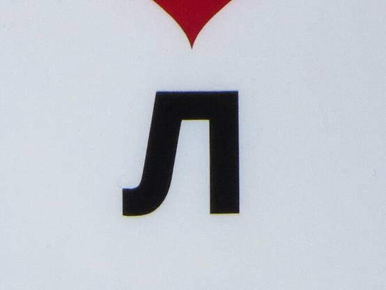 Чёрная буква Л на белом фоне, фрагмент вывески. // Black letter Л (Cyrillic L) on a white background, fragment of a signboard.