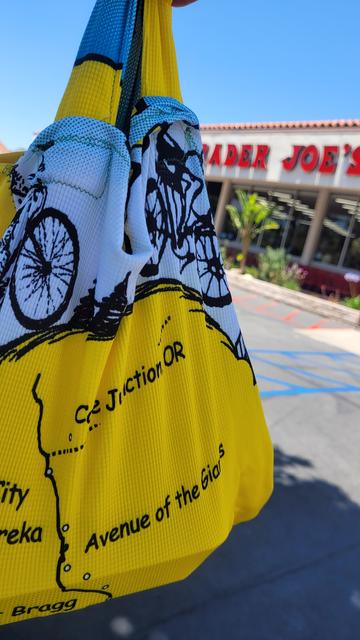 Yellow shopping bag made out of an old bicycle jersey in front of a Trader Joe's