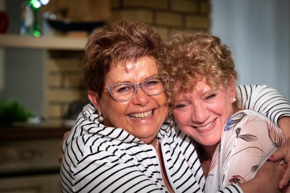 Two women in their sixties smiling and hugging each other.
