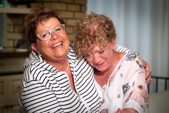 Picture of two women in their sixties, laughing and hugging each other.